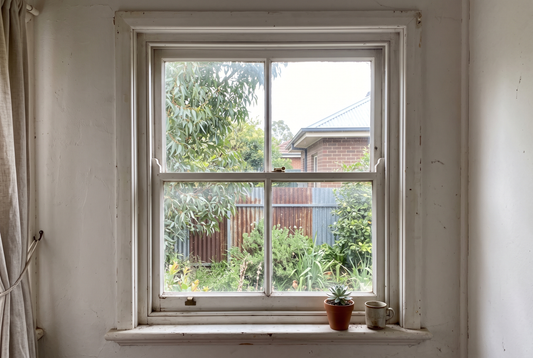A white painted timber double hung sash window seen from inside an older Australian home
