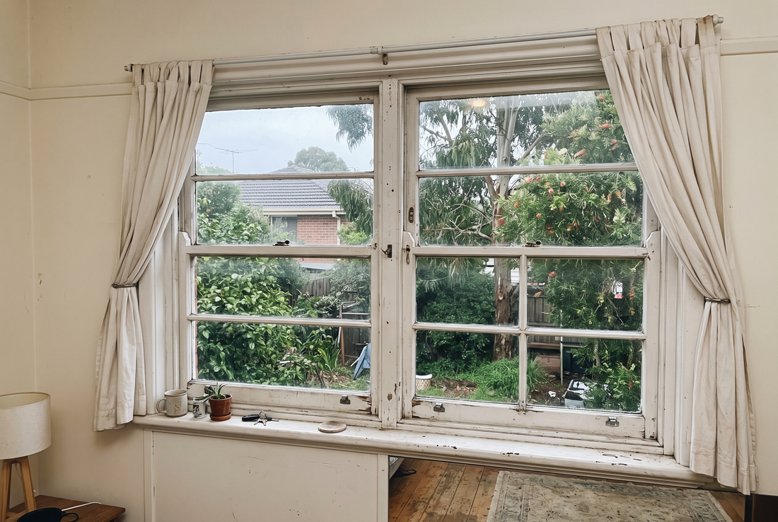 Old white timber double hung sash window in an Australian home seen from inside