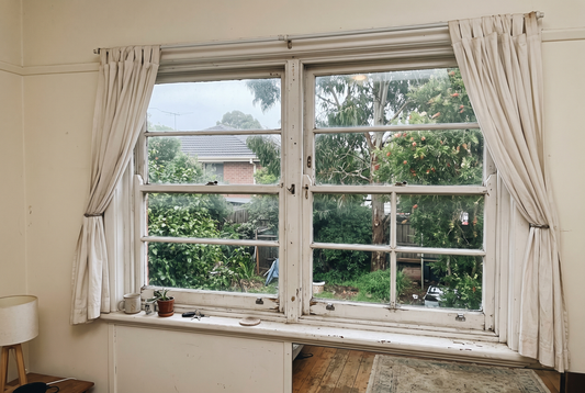 Old white timber double hung sash window in an Australian home seen from inside