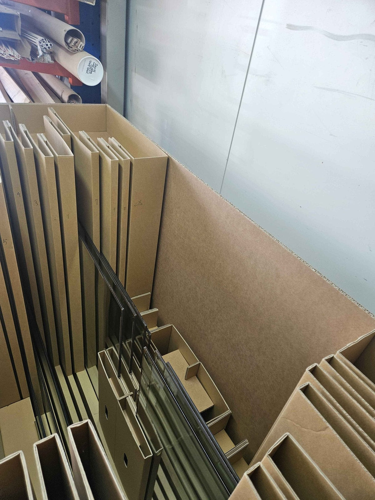 Numbered cardboard sleeves separating individual vacuum glass panes inside a shipping crate