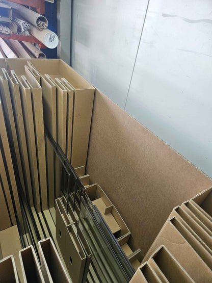 Numbered cardboard sleeves separating individual vacuum glass panes inside a shipping crate
